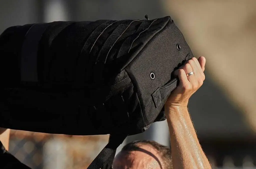 man holding black rucksack over head